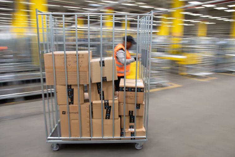 An Amazon sorting employee pulls a cart with parcels in a distribution center.