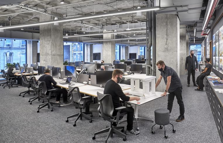 The main desk area includes model-making equipment and a 70-foot-long cork board for posting designs.