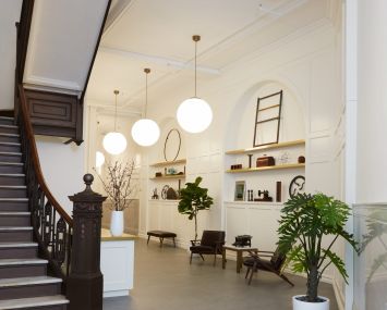 The block-through lobby at 22 West 19th Street has been renovated with new shelving and panelling on the walls, new globe light fixtures, and a seating area.