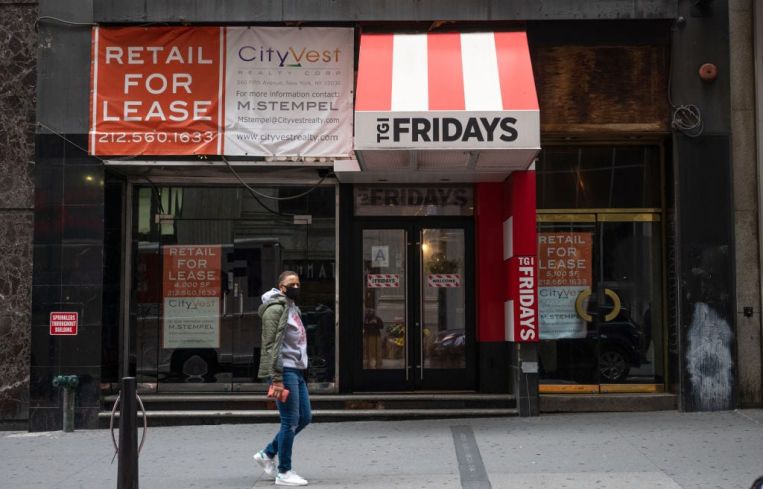 A person wearing a mask walks past a For Lease sign at a closed down TGI Fridays in the Financial District on October 22, 2020 in New York City.