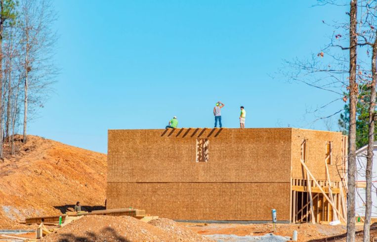 Workers stand a top a new house in Alabama.