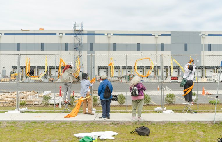 A group of union advocates write "Union" onto a fence erected around Amazon's JFK8 Staten Island Warehouse.