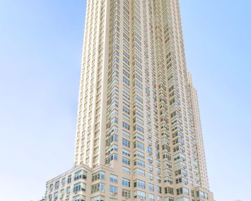 A large white and glass building jutting into an empty blue sky.