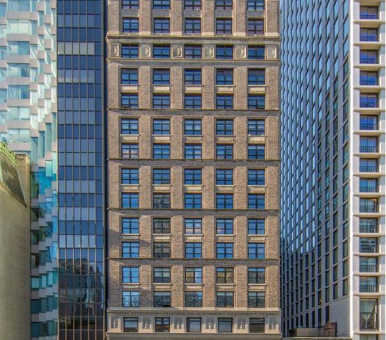 A 20-story Manhattan building made of grey stone and small-ish windows.
