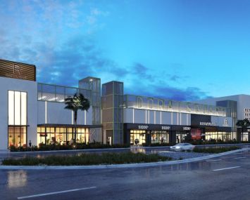 A large mall building in front of a sunset.