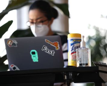 Hand sanitizer and wipes sit on the desk of an employee of a tech startup company.