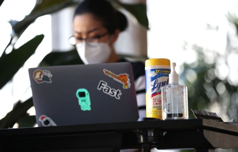Hand sanitizer and wipes sit on the desk of an employee of a tech startup company.