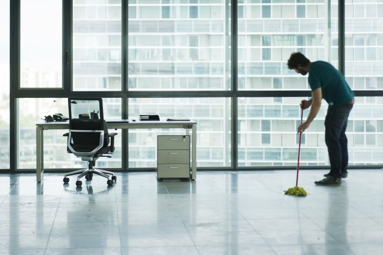 A lone man mopping an office floor.