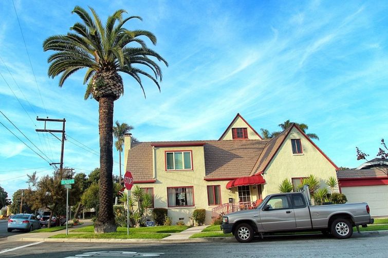 a suburban yellow and red home near a palm tree.
