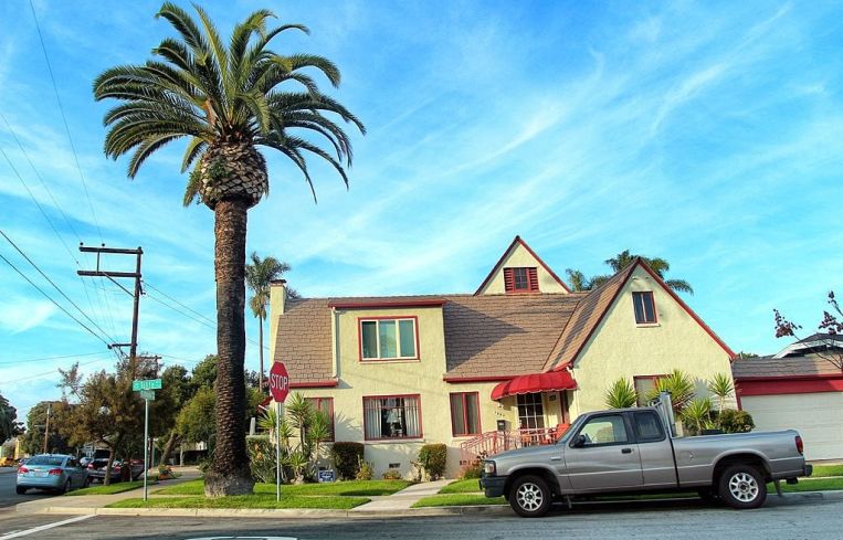 a suburban yellow and red home near a palm tree.