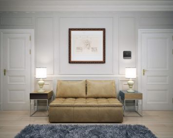 An apartment with a yellow, centered couch and two lamps on either side.