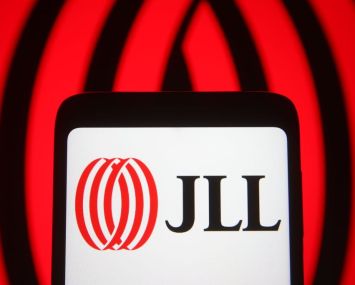 In this photo illustration the Jones Lang LaSalle Incorporated (JLL) logo of a global commercial real estate services company is seen on a smartphone and a pc screen.