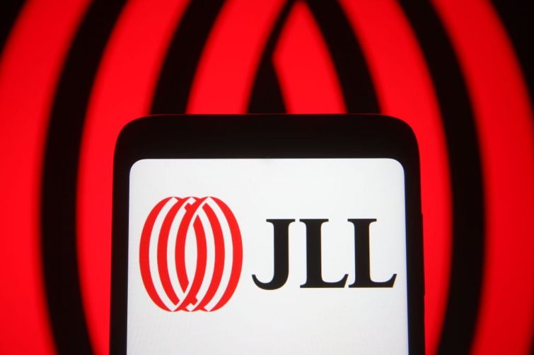 In this photo illustration the Jones Lang LaSalle Incorporated (JLL) logo of a global commercial real estate services company is seen on a smartphone and a pc screen.