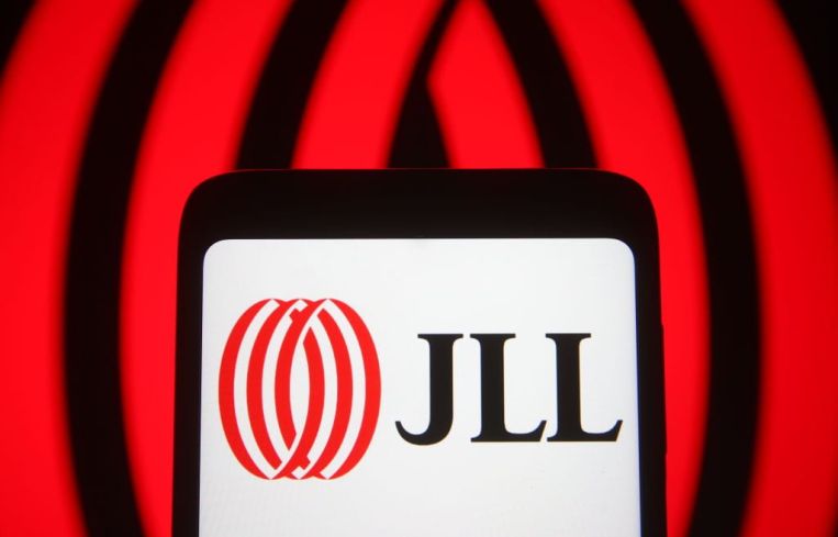 In this photo illustration the Jones Lang LaSalle Incorporated (JLL) logo of a global commercial real estate services company is seen on a smartphone and a pc screen.