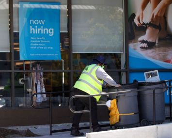 Worker in front of now hiring sign