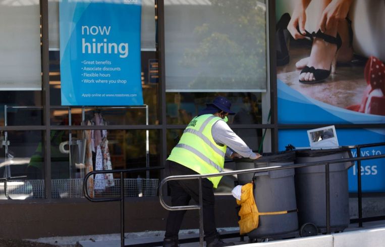 Worker in front of now hiring sign