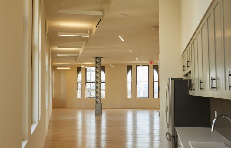 The 19th floor has been renovated into a marketing center with a modern gray and black office kitchen.