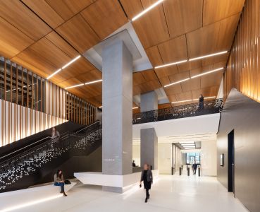 The new lobby is double height and includes a wood paneled ceiling and reinforced columns that were integrated into the new reception desk.