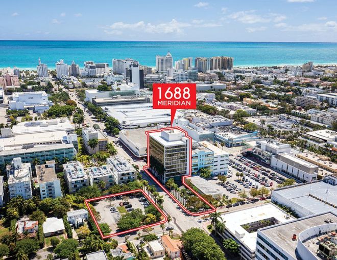 A building and two parking lots highlighted in red with a backdrop of an aerial view of Miami Beach.