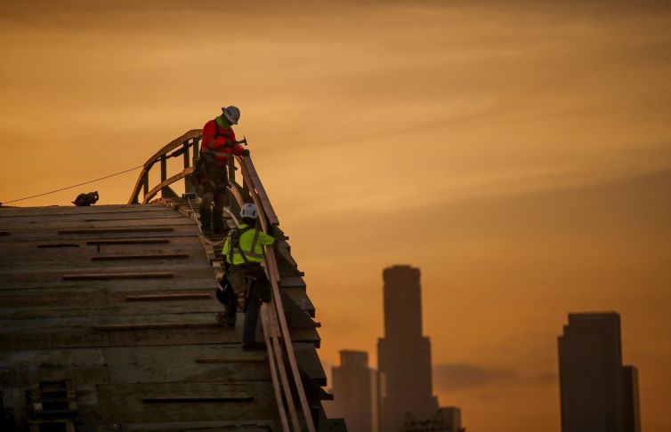 With a view of the Los Angeles skyline at sunset, a construction crew works on the Sixth Street Viaduct Replacement Project that crosses the 101 Freeway and Los Angeles River. The bridge is an on-going $588 million replacement project scheduled for completion in Summer of 2022.