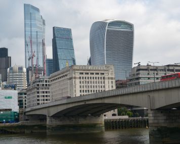 A city skyline beyond a concrete bridge over a river.