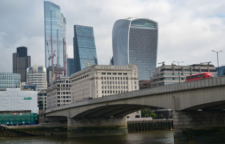 A city skyline beyond a concrete bridge over a river.