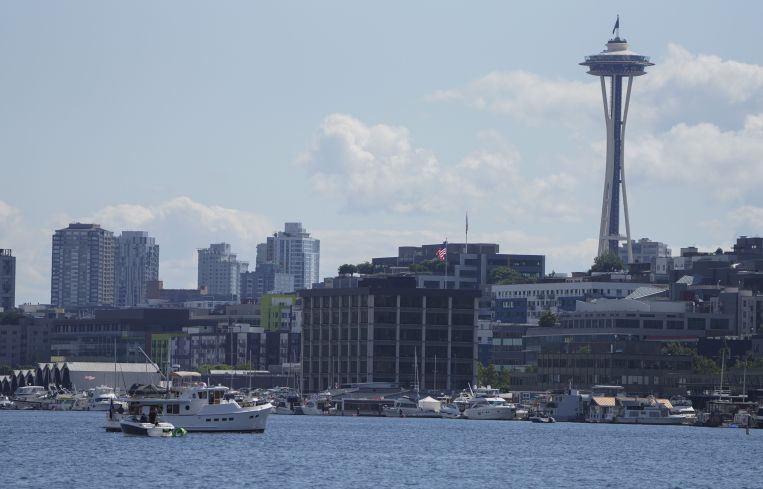 The skyline of a city on the water's edge, with a giant needle-like structure.