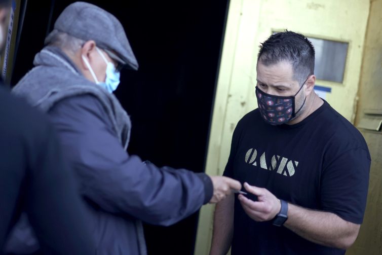 A doorman at Oasis checks a customer's vaccination card before allowing him to enter on July 29. As COVID-19 begins to surge due to the Delta variant, The San Francisco Bar Owner Alliance, which consists of over 500 bars in San Francisco, is implementing a new policy that requires bar customers to show proof of vaccination or a negative COVID-19 test within 72 hours of the bar visit.