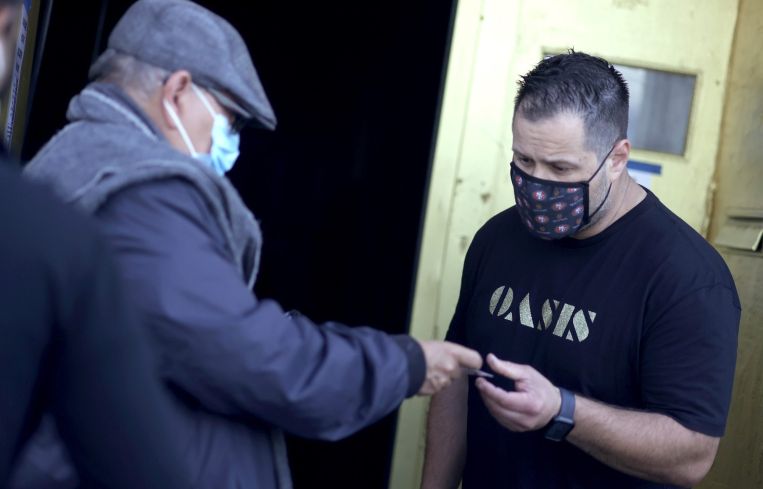 A doorman at Oasis checks a customer's vaccination card before allowing him to enter on July 29. As COVID-19 begins to surge due to the Delta variant, The San Francisco Bar Owner Alliance, which consists of over 500 bars in San Francisco, is implementing a new policy that requires bar customers to show proof of vaccination or a negative COVID-19 test within 72 hours of the bar visit.
