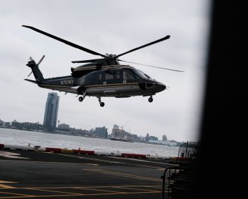 A helicopter taking off next to a river.