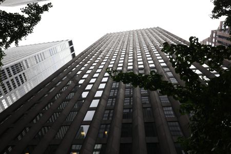 A tall building soaring toward the sky and viewed from the street.