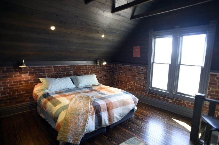 A very clean room with a brick wall and a bed.