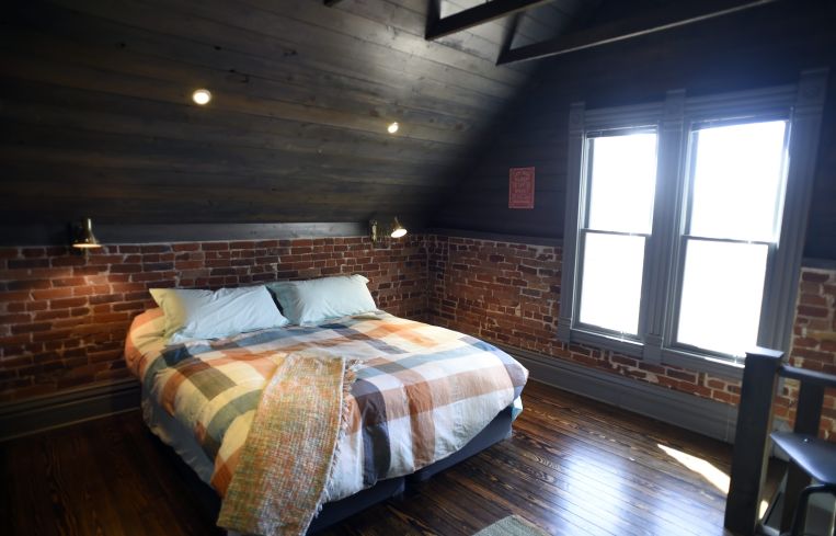 A very clean room with a brick wall and a bed.