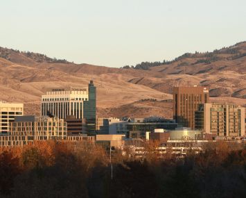 A skyline of squat buildings with mountains behind.