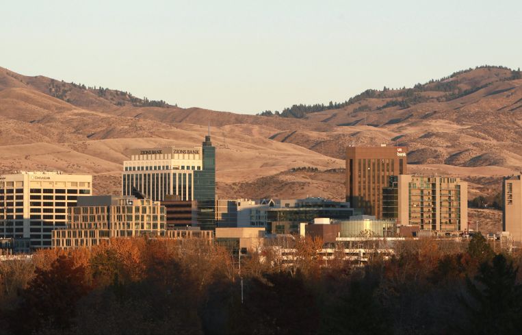 A skyline of squat buildings with mountains behind.