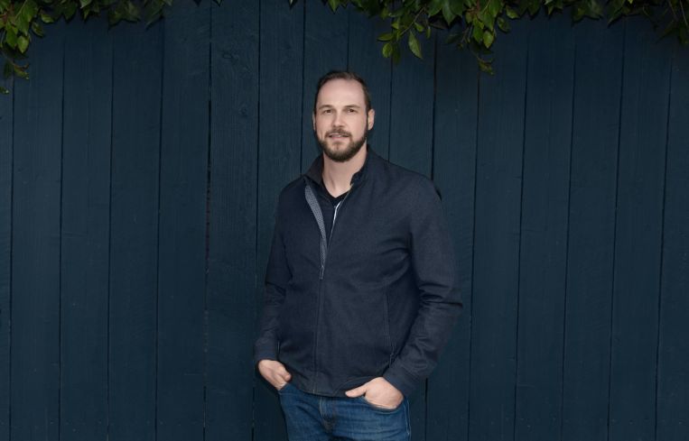A man standing and facing the camera, hands in pockets.