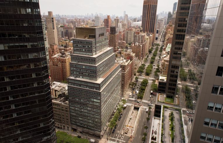 A tall, rectangular silver building in Midtown with a large, rectangular base and several slightly smaller floors as the building rises.