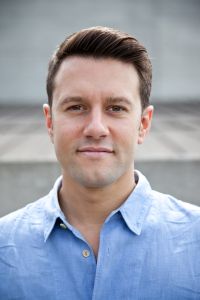 A closeup of a man's face, and he's kind of smiling.