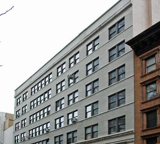 A large grey office building on an empty street.