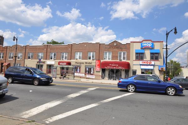 An IHop seen from across the street as two cars pass.