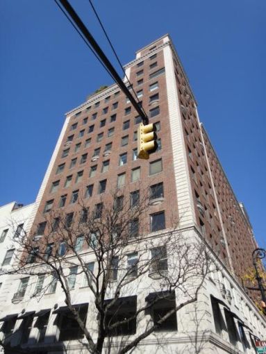 A large brown building with a traffic light in the foreground in front of it.