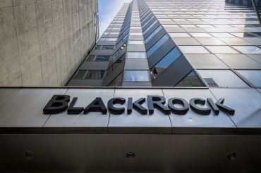 A large skyscraper ascends into the blue sky with the name "BlackRock" on the lowest level.