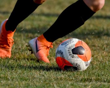 A detail photo of a player's feet dribbling a soccer ball.