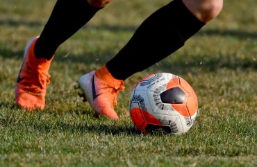 A detail photo of a player's feet dribbling a soccer ball.