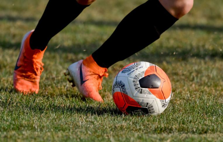A detail photo of a player's feet dribbling a soccer ball.