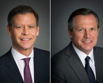 Two men smiling side by side.