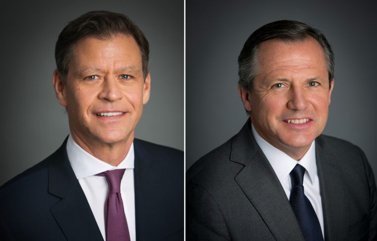 Two men smiling side by side.