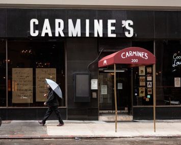 A person holds an umbrella outside Carmine's Italian Restaurant in Times Square