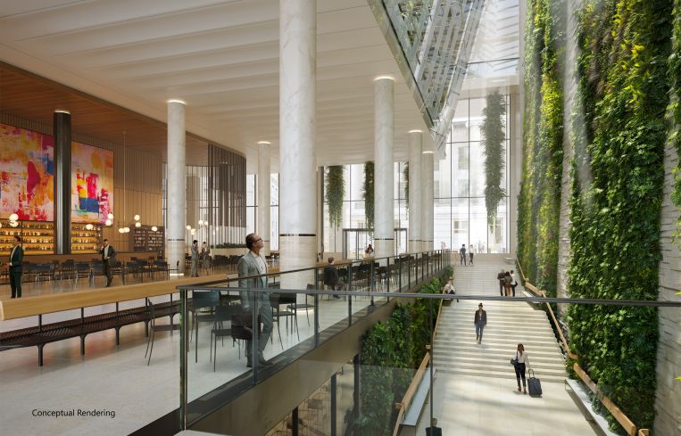 A large open atrium with a green, plant-covered wall and pillars.