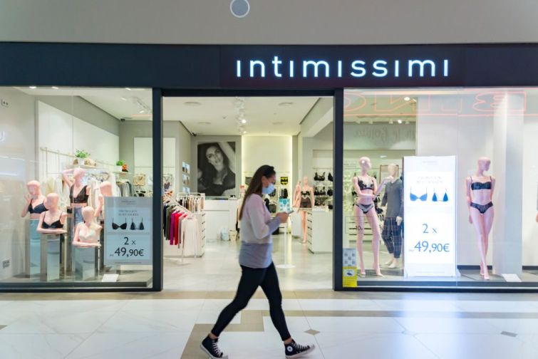 A woman with a mask walking in front of the Intimissimi